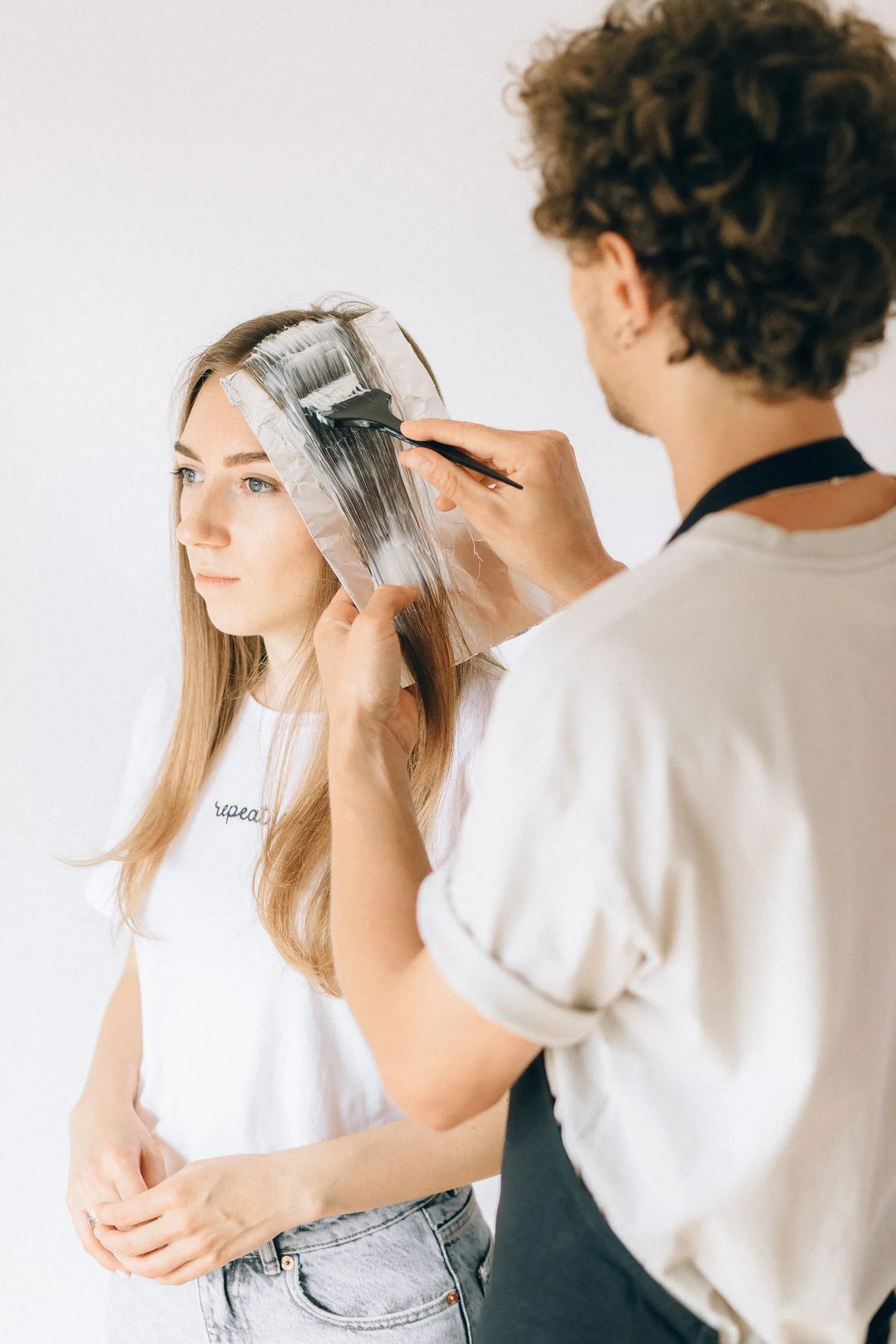 Hairstylist applying dye to a client's hair using the foil highlighting technique in a salon
