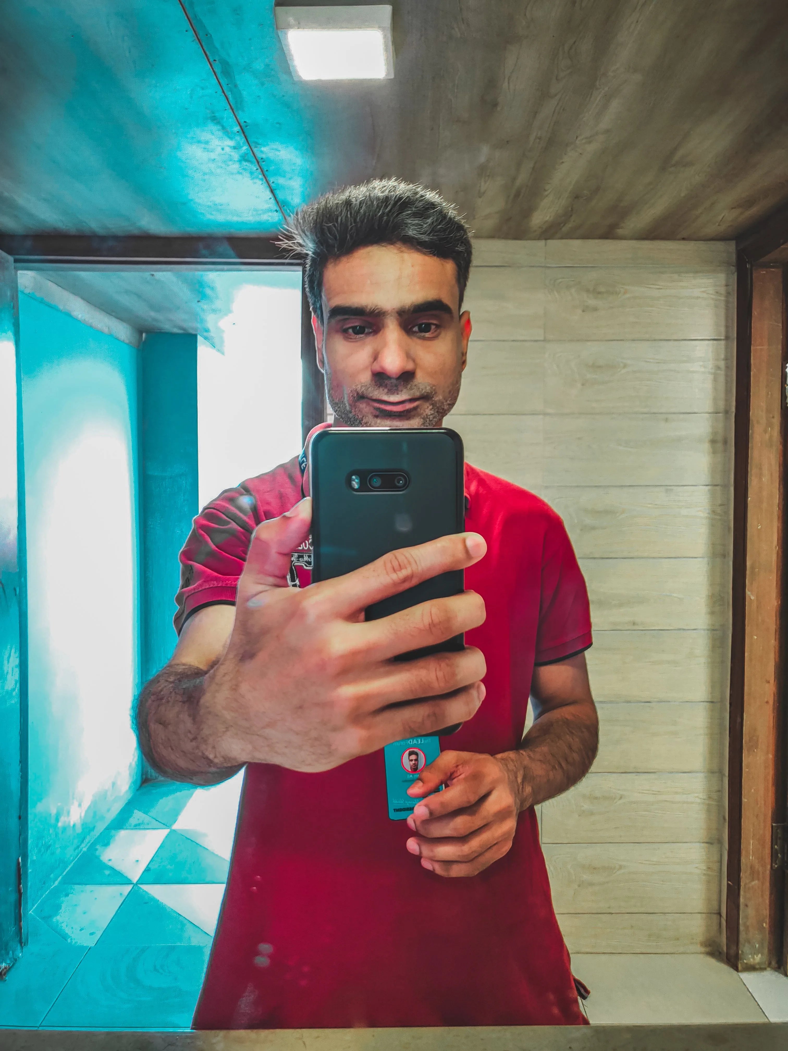 A man taking a selfie of himself in a bathroom mirror with his smartphone, documenting his appearance over time