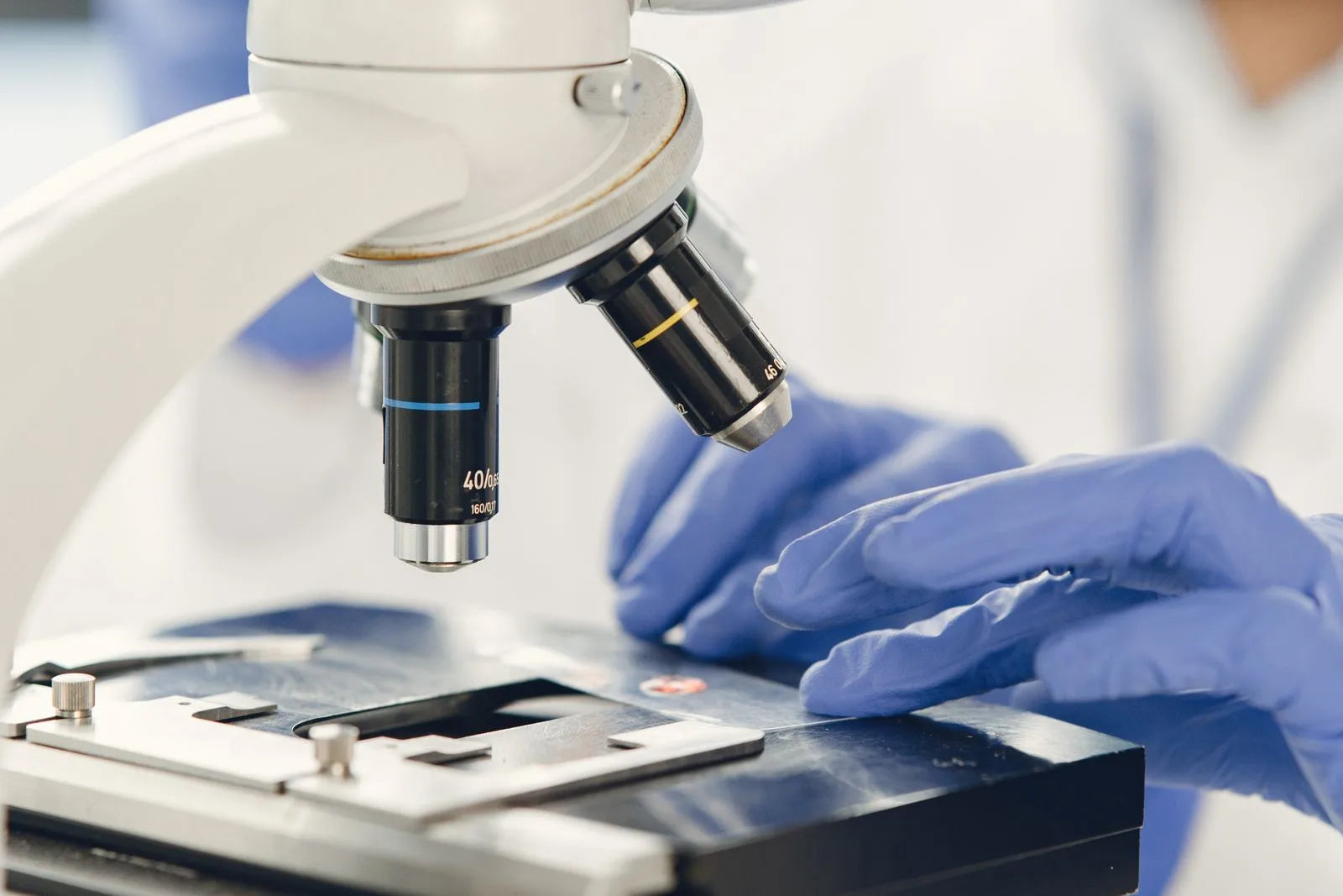 Close-up of a scientist's hands examining a specimen under a laboratory microscope, illustrating molecular research into TGF-beta signaling pathways