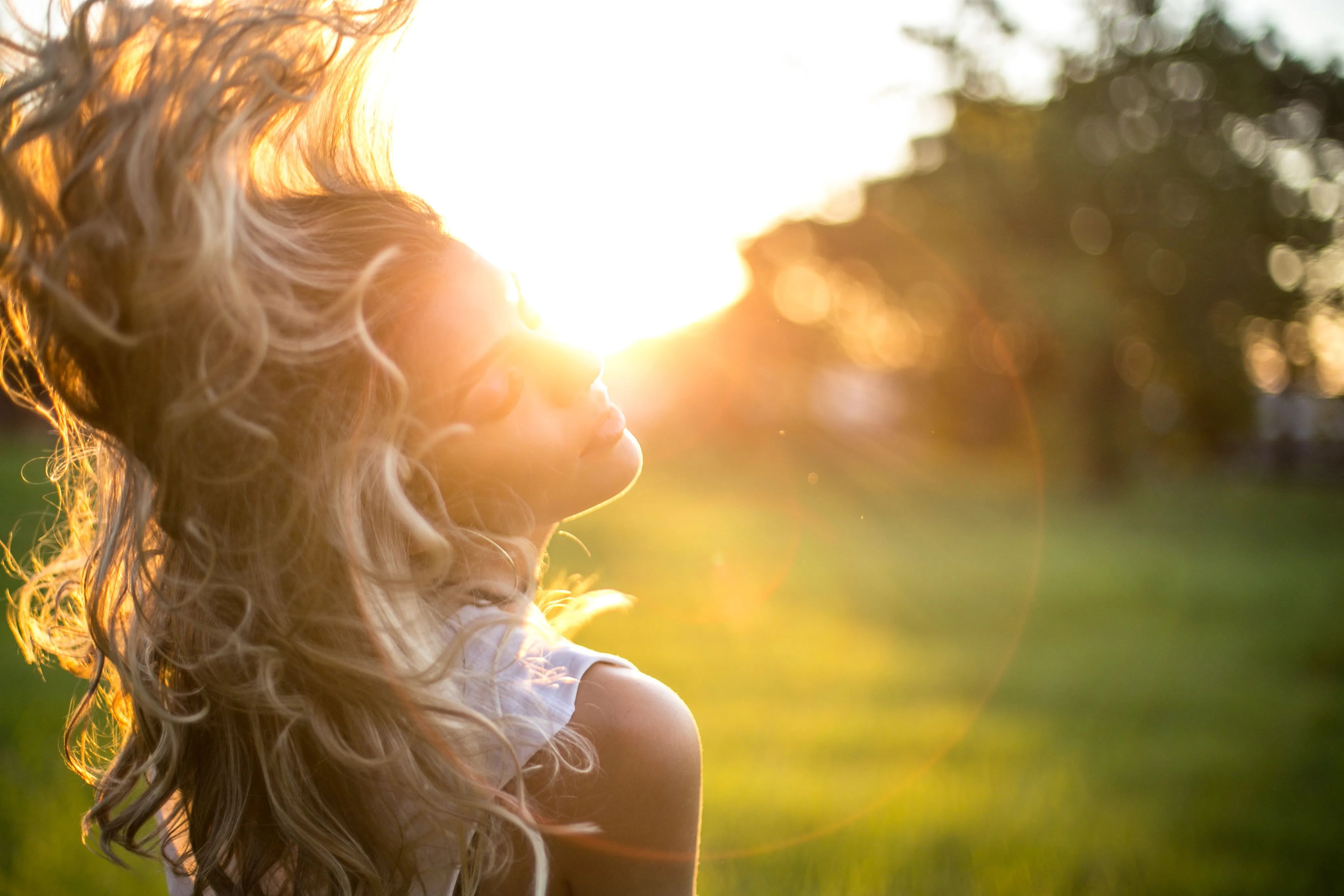 Woman with long wavy hair caught in motion, sunlight streaming through it during golden hour outdoors